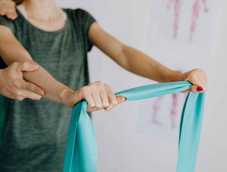 Woman guided by physiotherapist to use exercise band